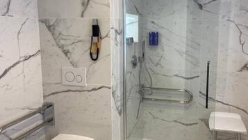 Ein modernes Badezimmer mit einer Duschkabine, einer Toilette und einem kleinen Hocker.