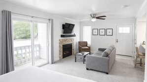 A hotel room with a bed, a fireplace, a sofa, a TV, and a ceiling fan.