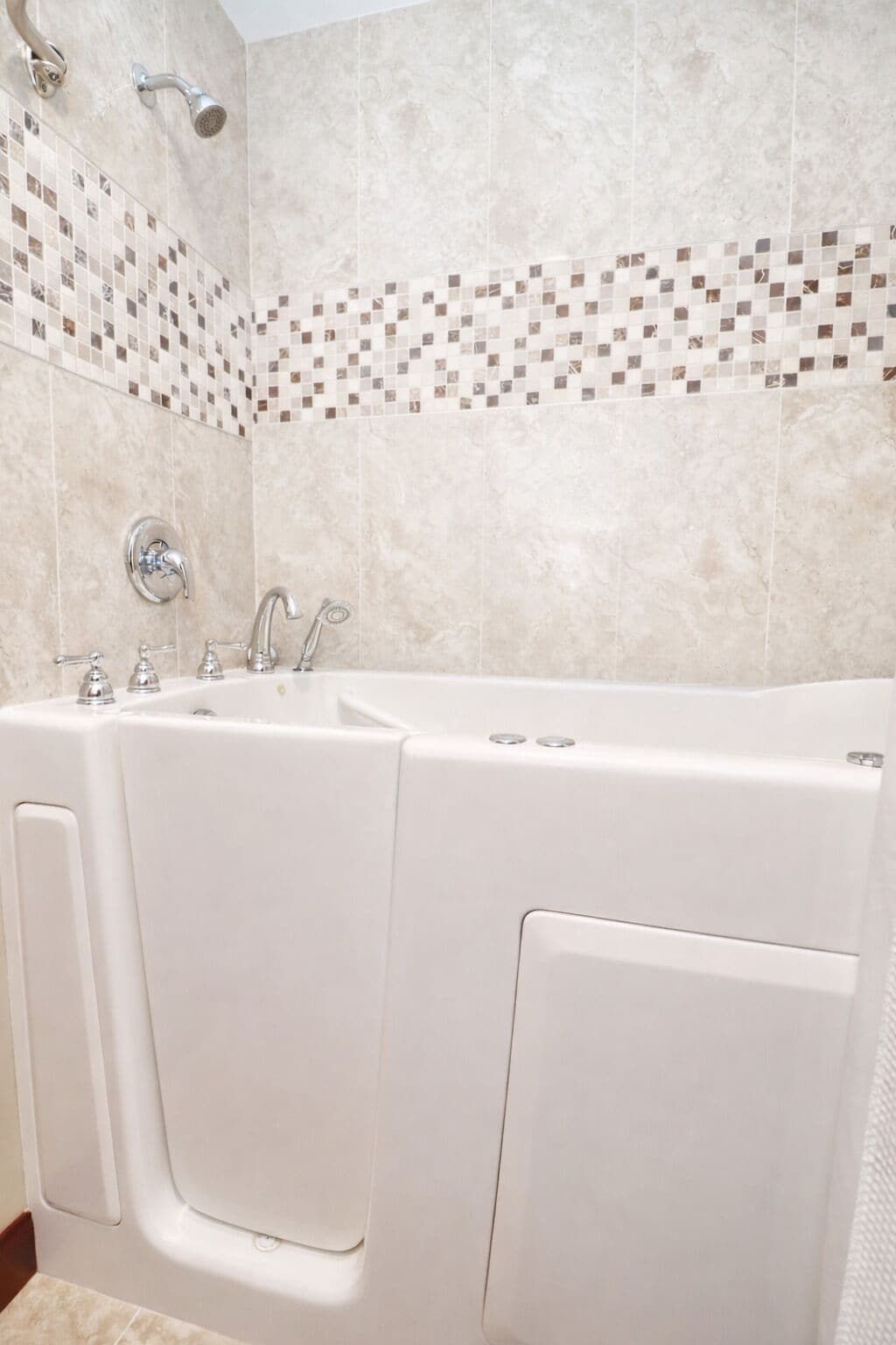Une salle de bain dotée d’une baignoire double, d’une douche et d’un mur recouvert de carreaux formant une mosaïque.