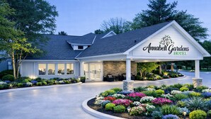 A hotel with a covered entrance, outdoor seating, and a landscaped garden.