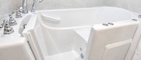 Una bañera blanca con cabezal de ducha y grifo, un panel de control y una cortina de ducha texturizada.