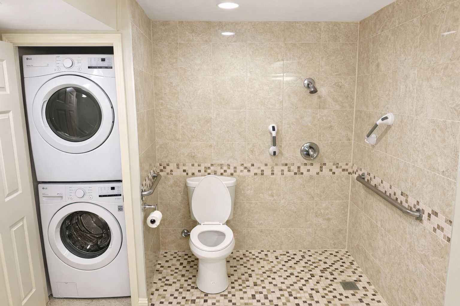 Un bagno con un water, due lavatrici, una doccia e pavimento piastrellato.