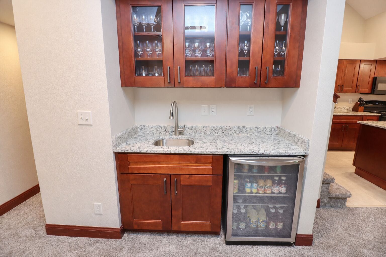 A kitchen with wooden cabinets, a granite countertop, a stainless steel sink, and a refrigerator with a freezer.