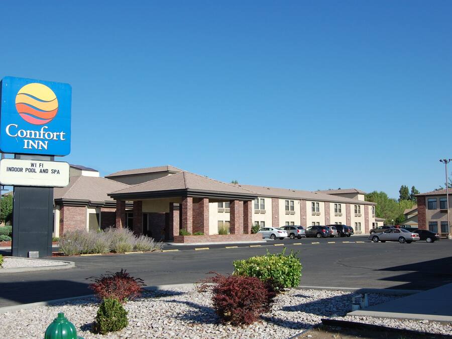 A Comfort Inn hotel with a sign indicating indoor pool and spa, a parking lot, and a clear blue sky.