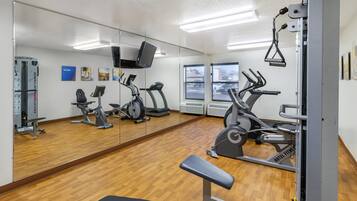 A gym with exercise equipment, a bench, and a large mirror.