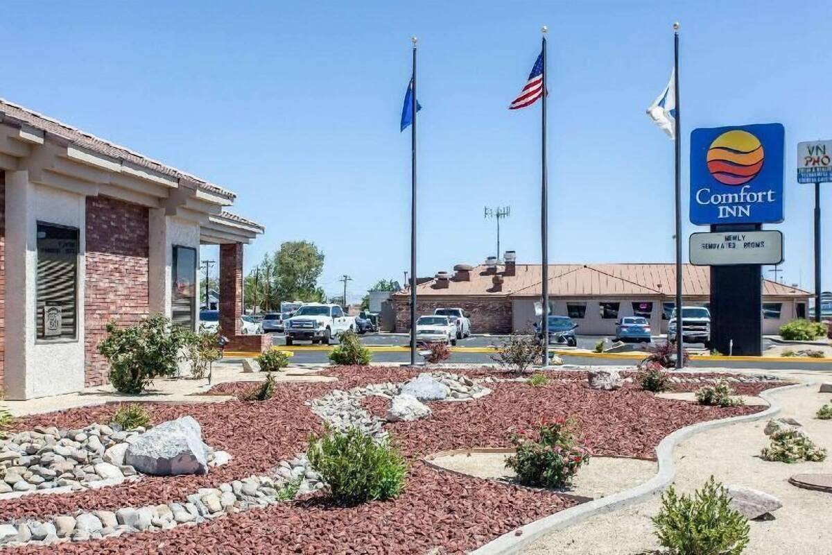 A Comfort Inn with a brick building, a parking lot, and a landscaped area with rocks and shrubs.