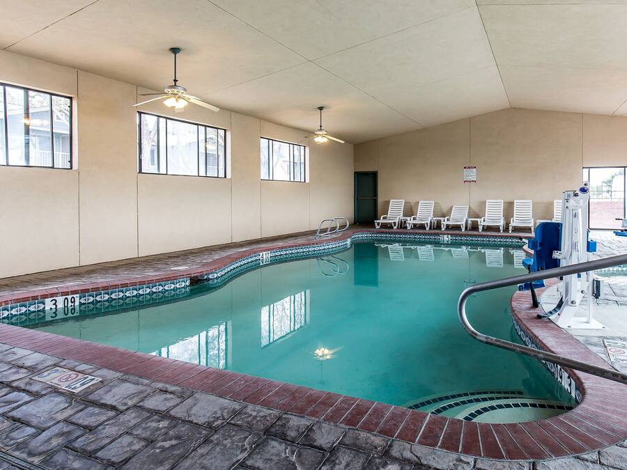 Una piscina interior con agua cristalina, una terraza con baldosas y sillones de descanso.