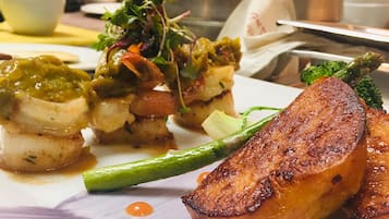 Une assiette de mets comprenant desSaint-Jacques poêlés, des légumes rôtis et des asperges grillées.