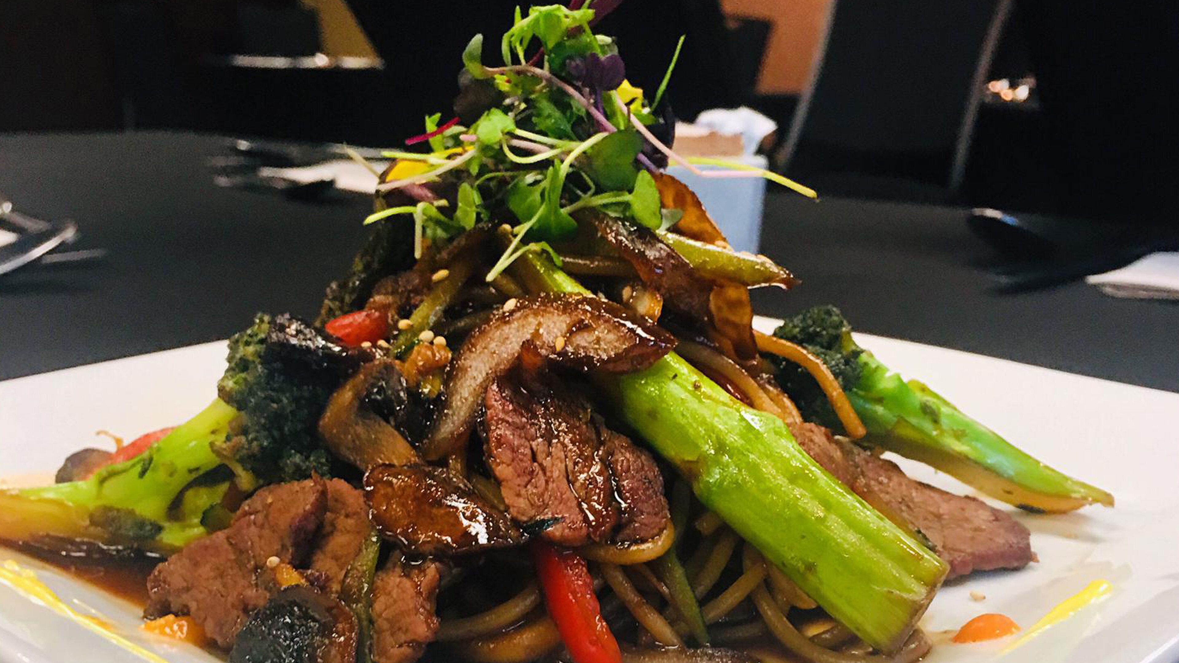 A plate of stir-fried beef with vegetables and noodles.