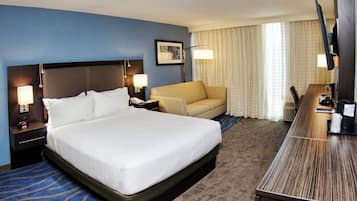 Una habitación de hotel con una cama grande, un sofá, un escritorio y una televisión.