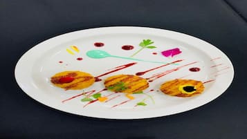 A white plate with three food items and artistic sauce drizzles.