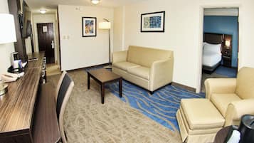 Une chambre d’hôtel équipée d’un canapé, d’un fauteuil, d’une table basse et d’un bureau avec un téléphone.