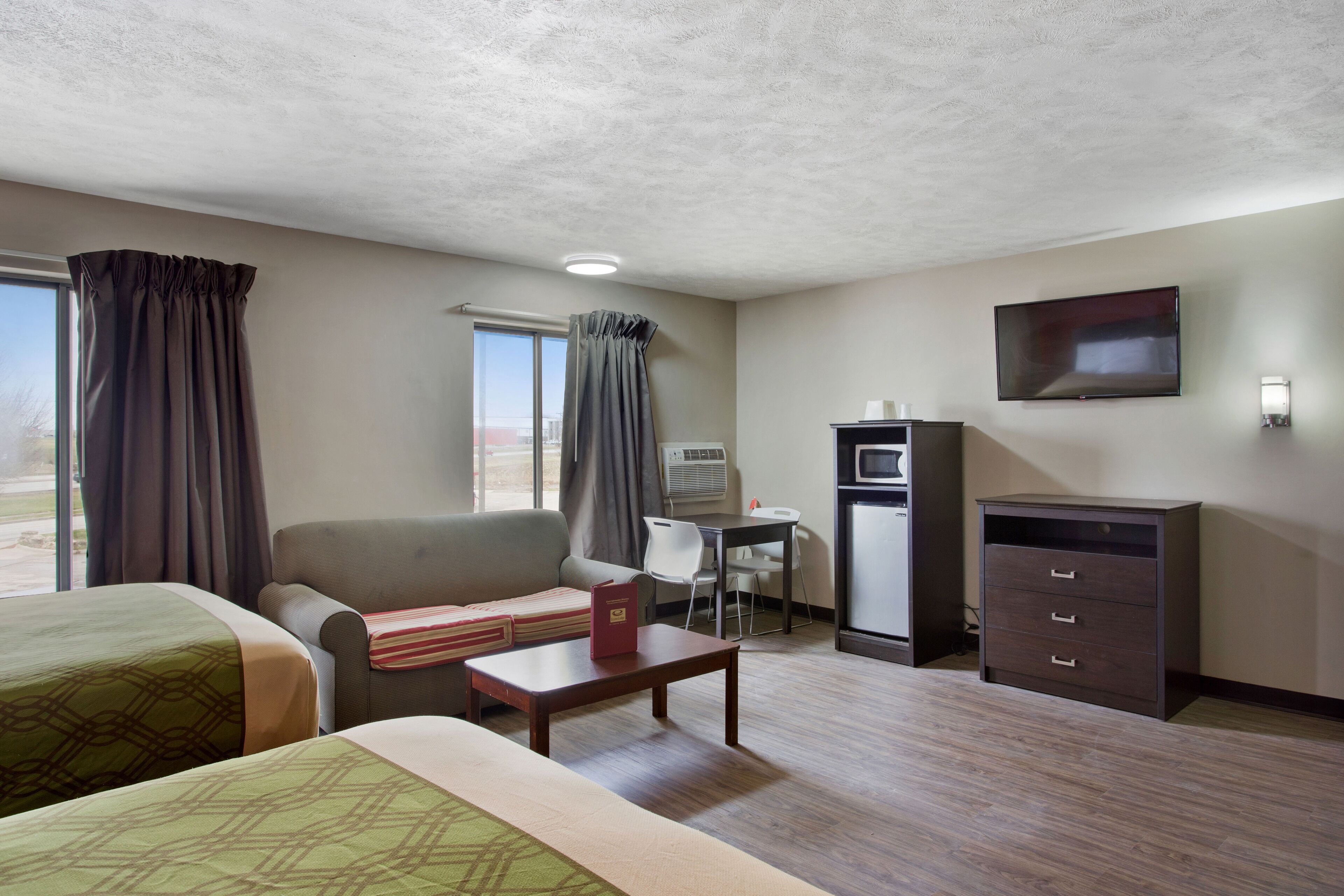 Habitación de hotel con dos camas, un escritorio, una silla, un televisor y un minibar.