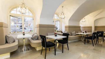 A dining area with a high arched ceiling, a white table with chairs, and a bench with cushions.