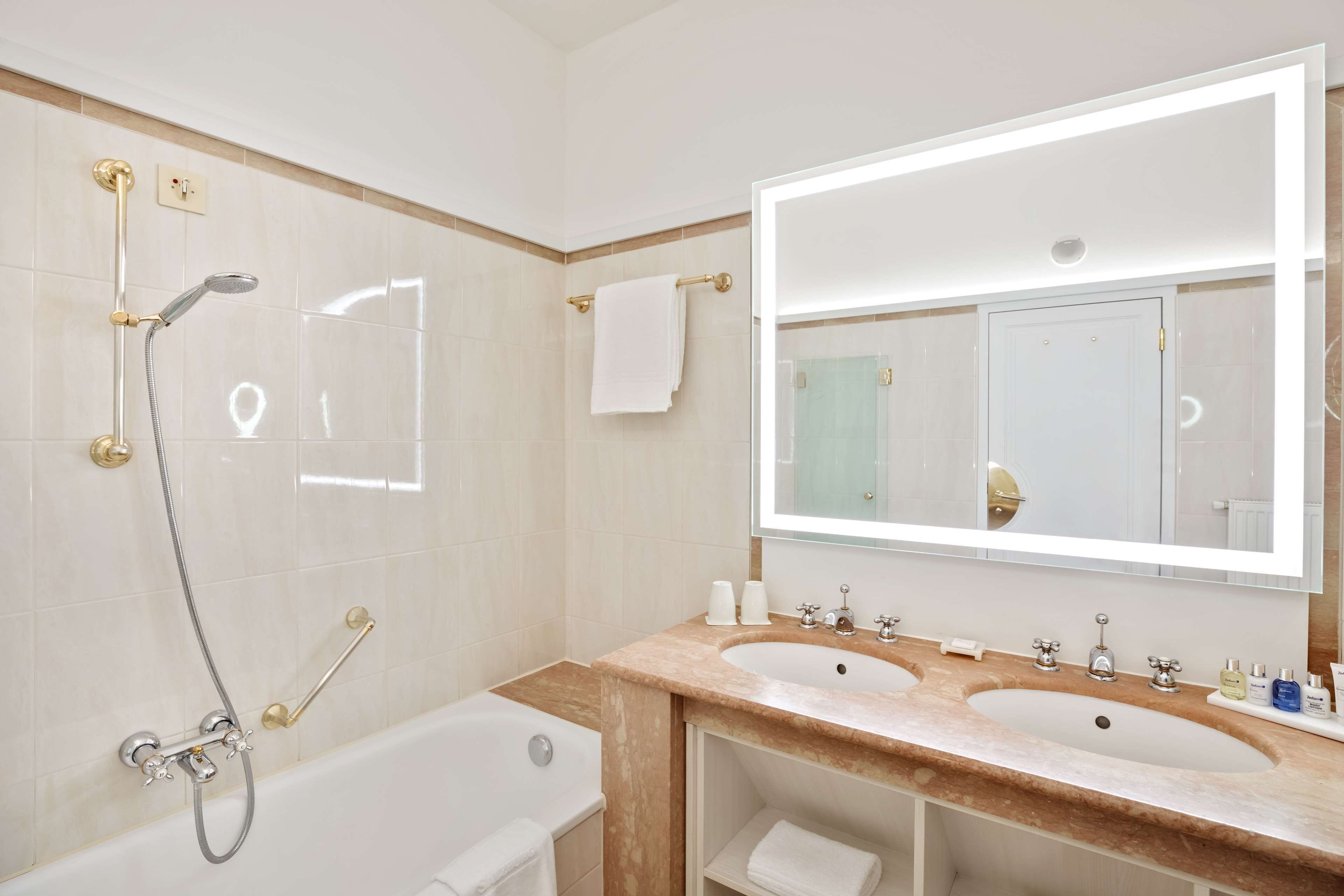A bathroom with two sinks, a bathtub, a shower, and a large mirror.