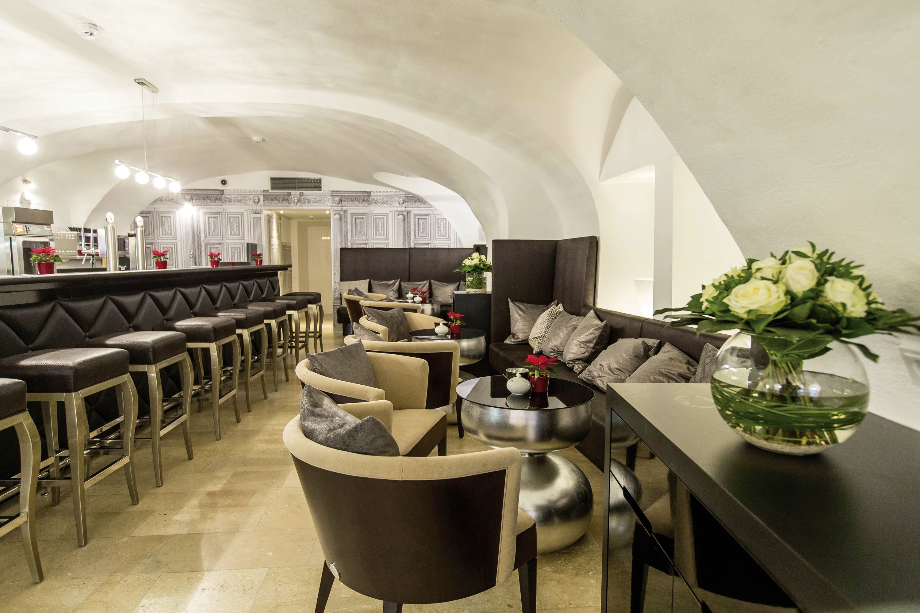 A spacious, modern interior with a bar area, seating, and a decorative vase.
