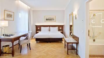Ein Hotelzimmer mit Bett, Schreibtisch, Stuhl und einem Badezimmer mit Badewanne und Dusche.
