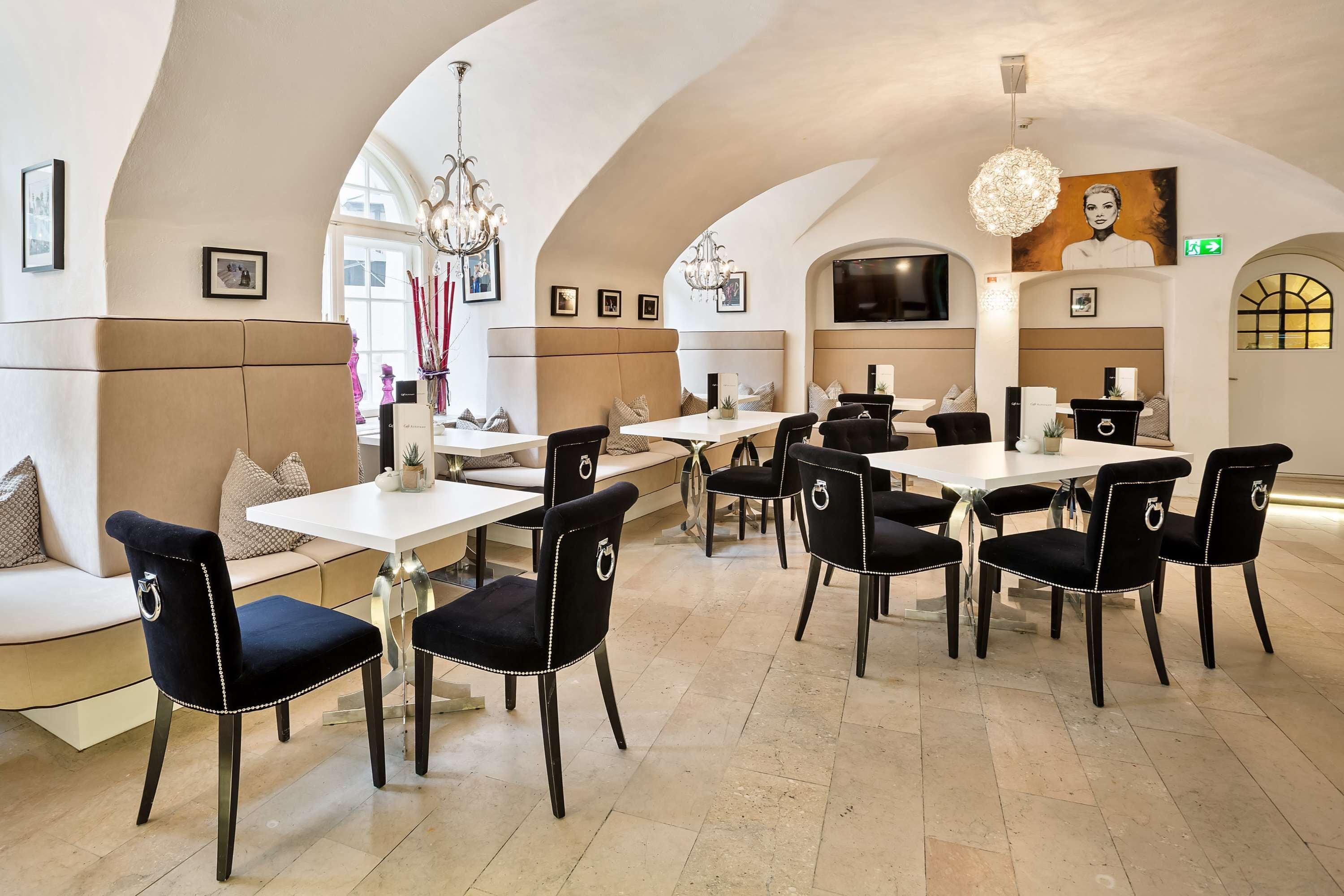 A dining area with high arched ceilings, white tables, and black upholstered chairs.