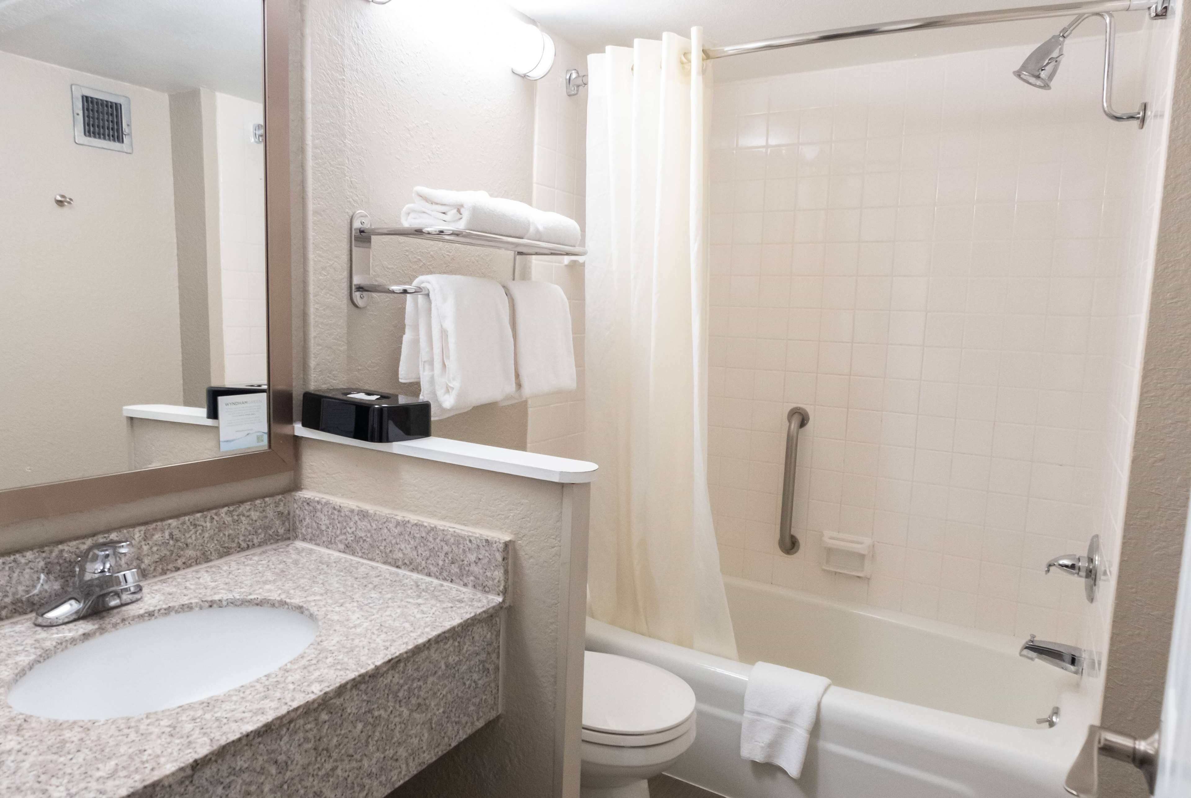 A bathroom with a granite sink, white toilet, and a walk-in shower with a glass door.