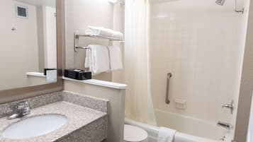 A bathroom with a granite sink, white toilet, and a walk-in shower with a glass door.
