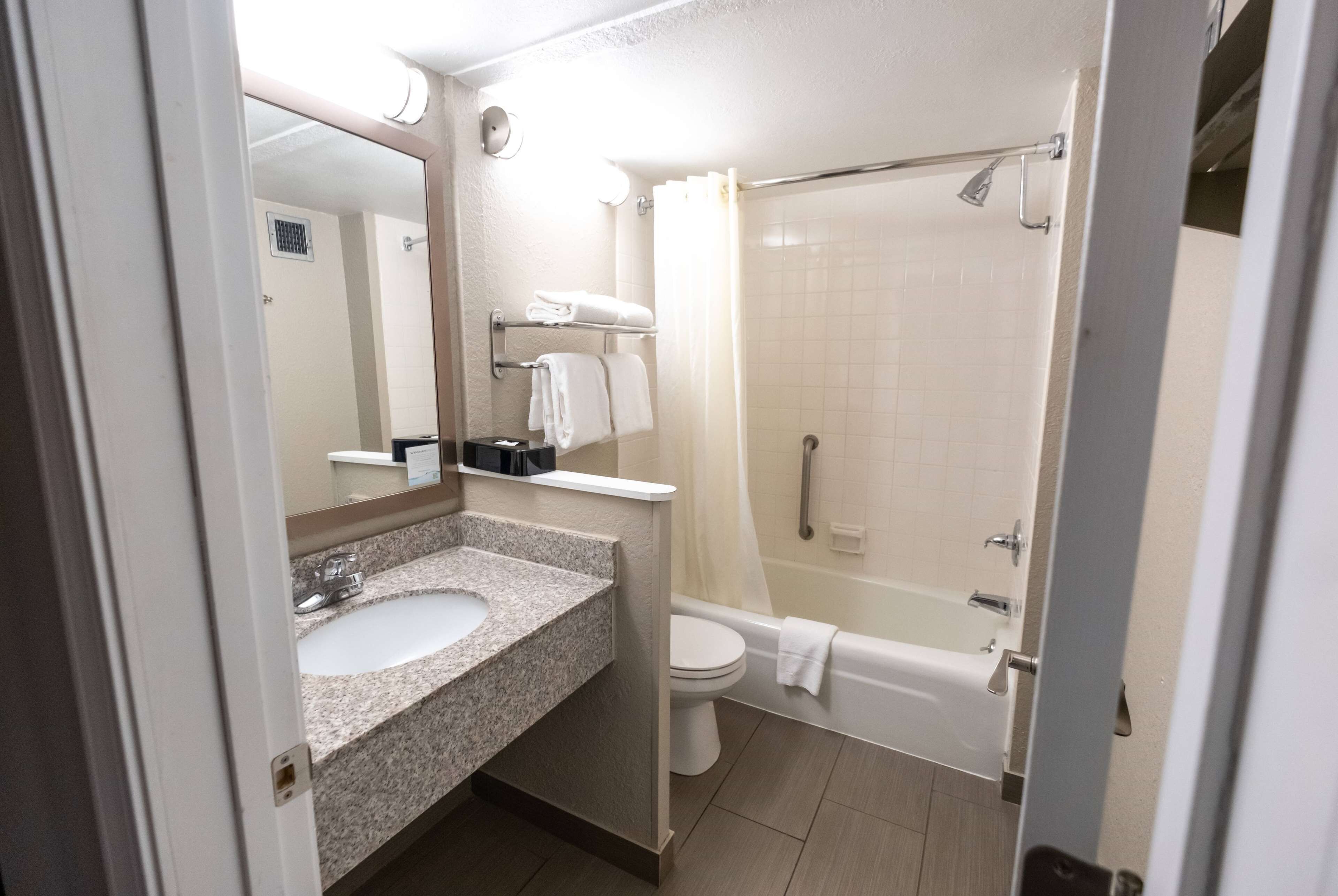 Un baño moderno con lavamanos de granito, inodoro y bañera.