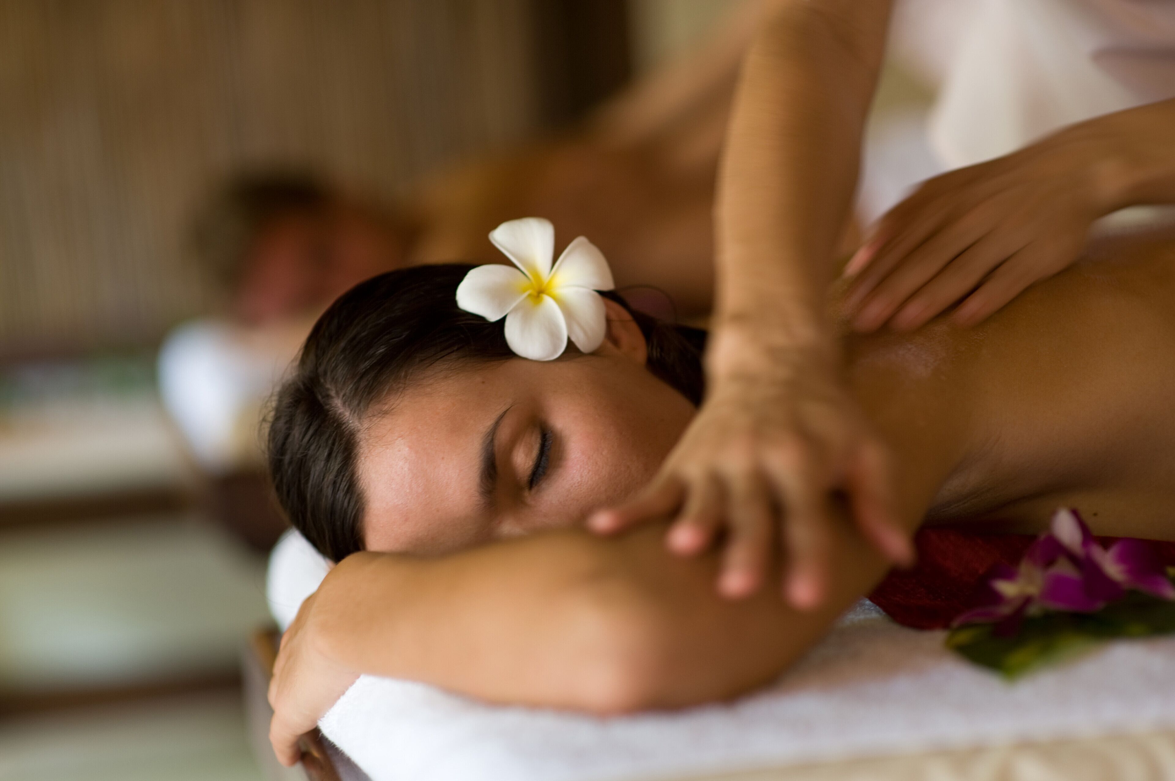 A person receiving a massage with a flower in their hair.