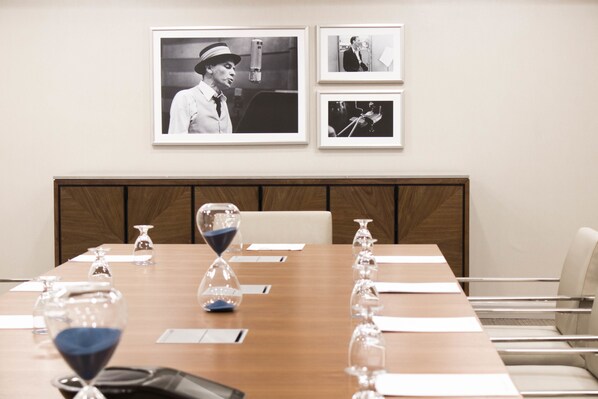Un salón de conferencias con una larga mesa, sillas y cuadros en la pared.
