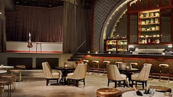 A bar area with a stage, bar stools, and a seating area with tables and chairs.