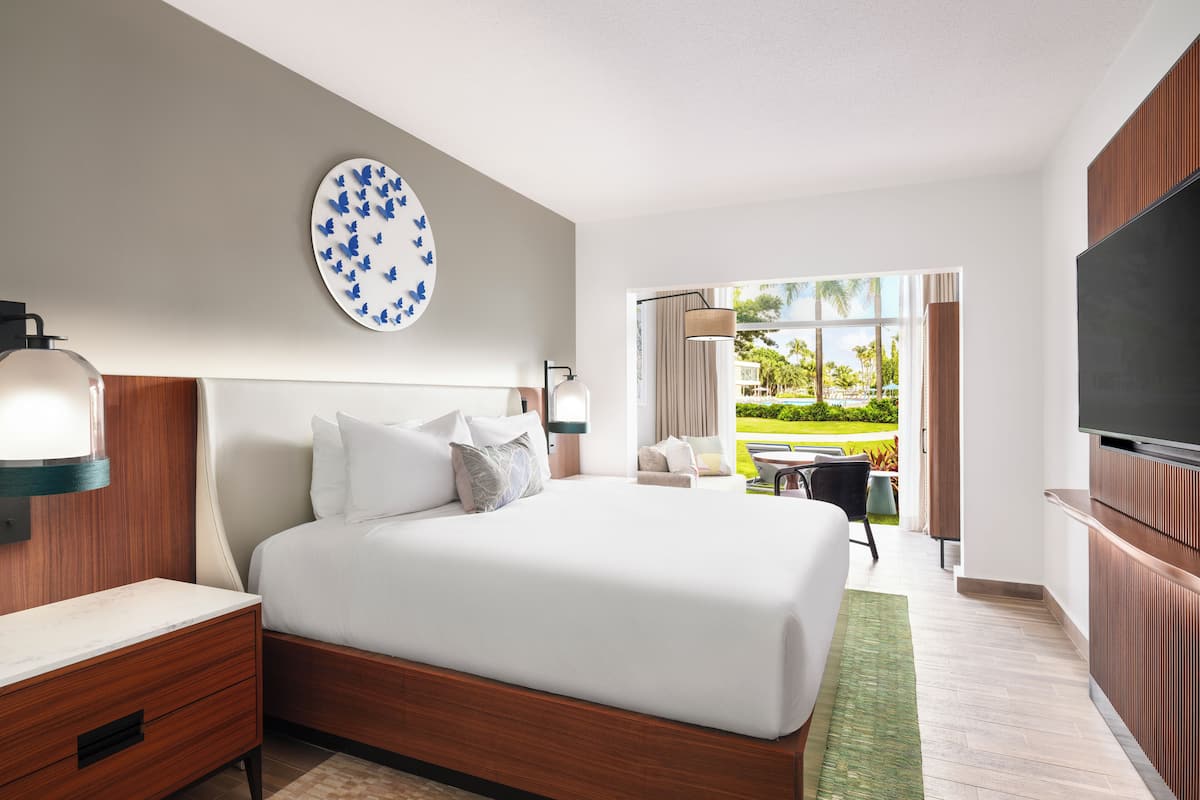 Une chambre d’hôtel moderne dotée d’un grand lit, d’un téléviseur à écran plat, d’un coin repas avec vue sur l’extérieur et d’une grande fenêtre.