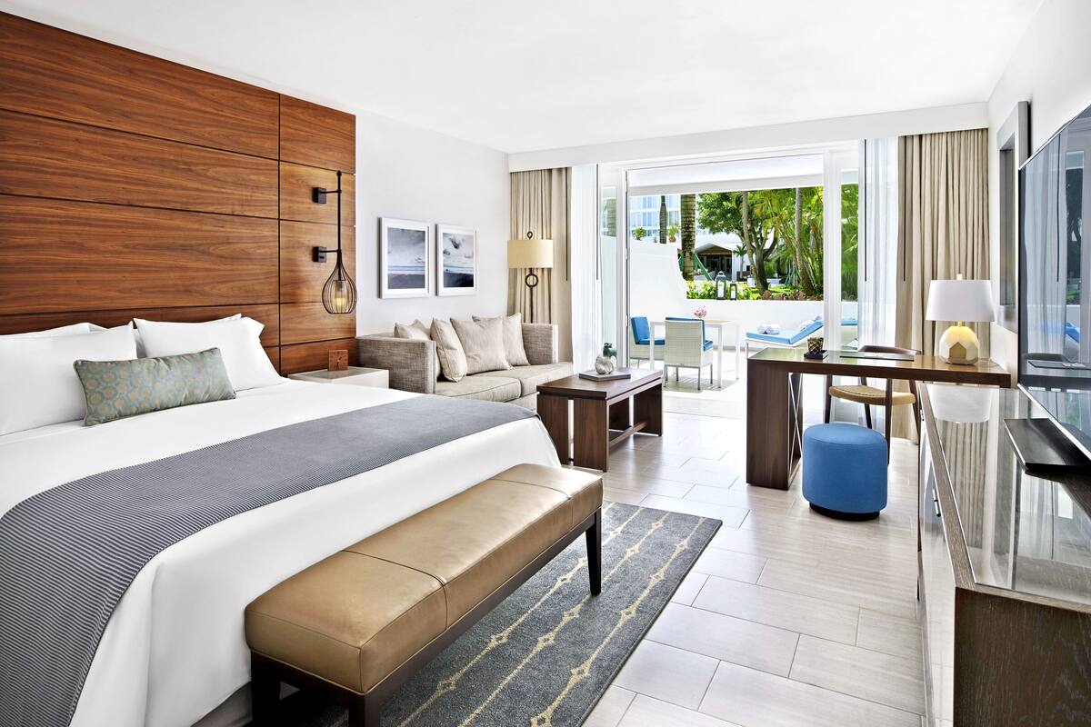 Une chambre d’hôtel moderne, dotée d’un grand lit, d’un canapé, d’un bureau et offrant une vue sur l’extérieur.