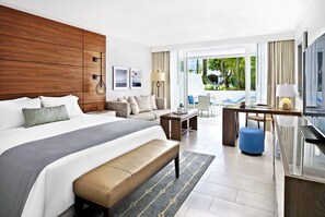 A modern hotel room with a large bed, a sofa, a desk, and a view of the outdoors.