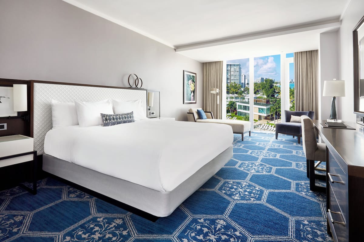Une chambre d’hôtel avec un grand lit, un bureau, une chaise et une vue sur la ville.