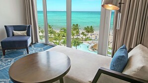 A hotel room with a large window offering a view of the ocean and a pool area. - Fairmont El San Juan Hotel (Carolina)