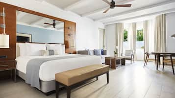 A modern hotel room with a large bed, a bench, a desk, and a balcony with curtains.