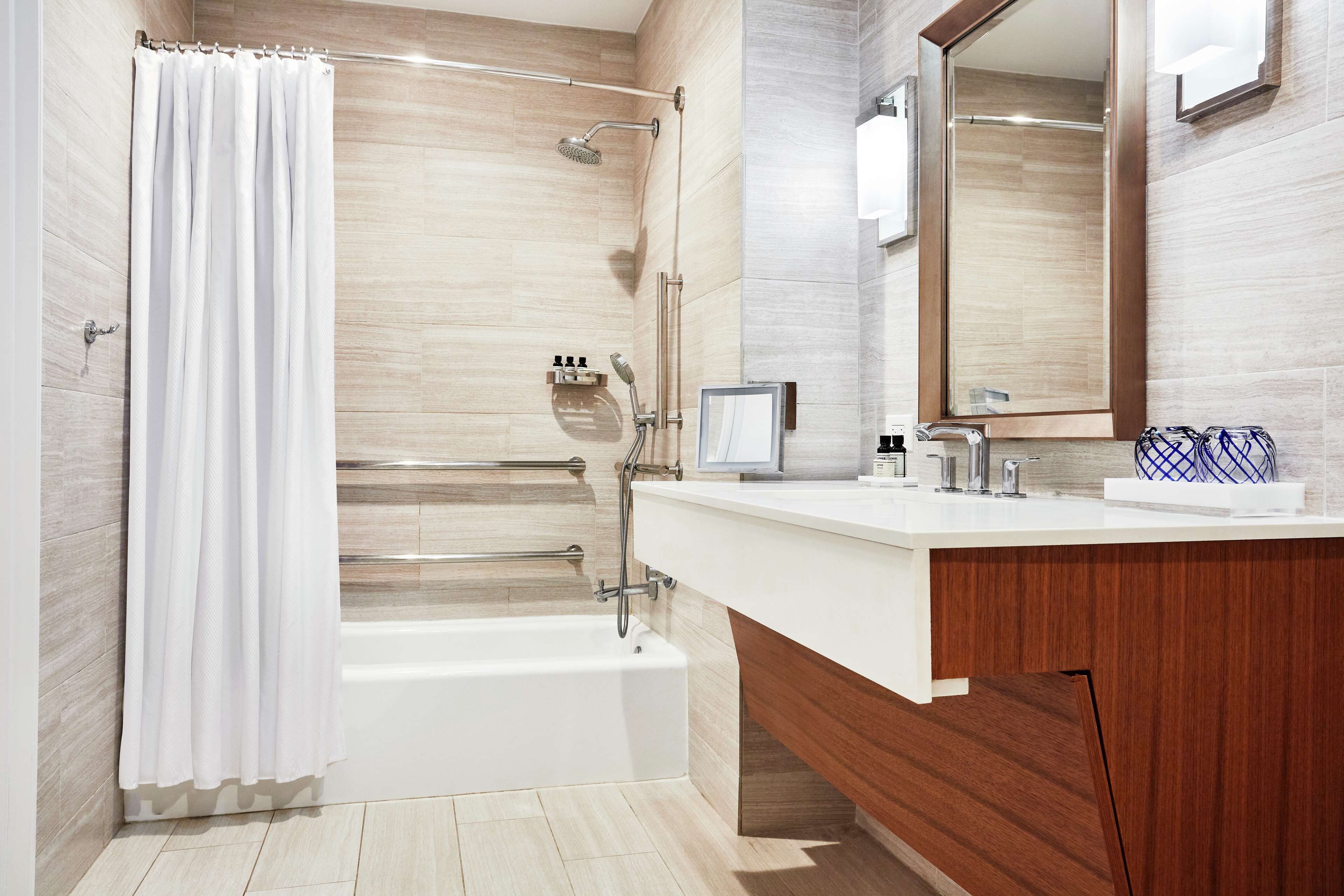 A modern bathroom with a bathtub, shower, vanity, and a large mirror.