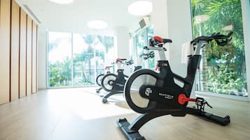 Une salle de sport équipée de vélos d’appartement, dotée de grandes fenêtres et d’un plancher en bois.