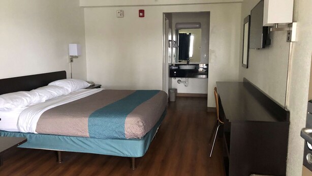 A hotel room with a bed, bedside table, lamp, and a view of the bathroom. - Days Inn by Wyndham Indianapolis South (Indianapolis)
