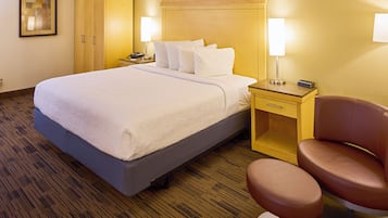 A hotel room with a bed, bedside tables, a chair, and a wardrobe.