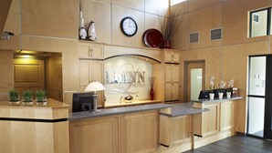 A hotel reception area with a wooden counter, a clock, and a sign that reads "LIVINN HOTELS". - LivINN Hotel Minneapolis South / Burnsville (Burnsville)