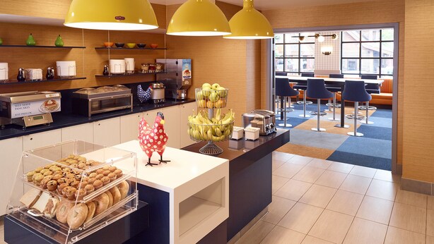 A breakfast bar with pastries, a self-serve pancake station, and a decorative chicken figure. - LivINN Hotel Minneapolis South / Burnsville (Burnsville)