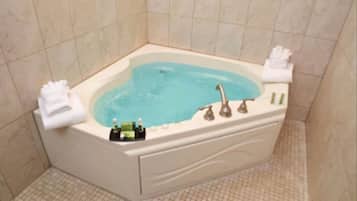 A corner bathtub with a built-in sink, a towel rack, and a bottle of shampoo.