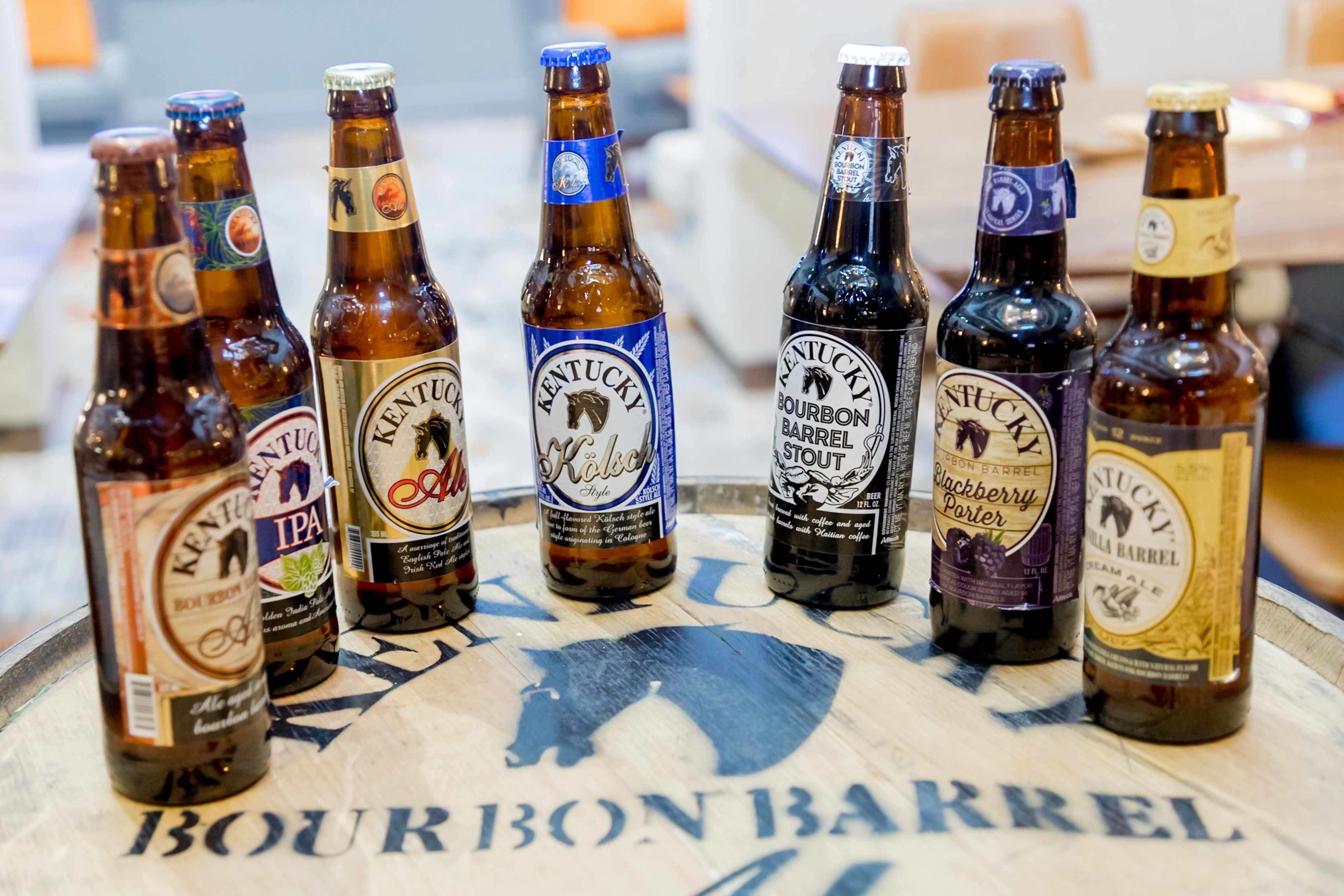 A selection of bourbon barrel beer bottles arranged on a barrel-shaped table.