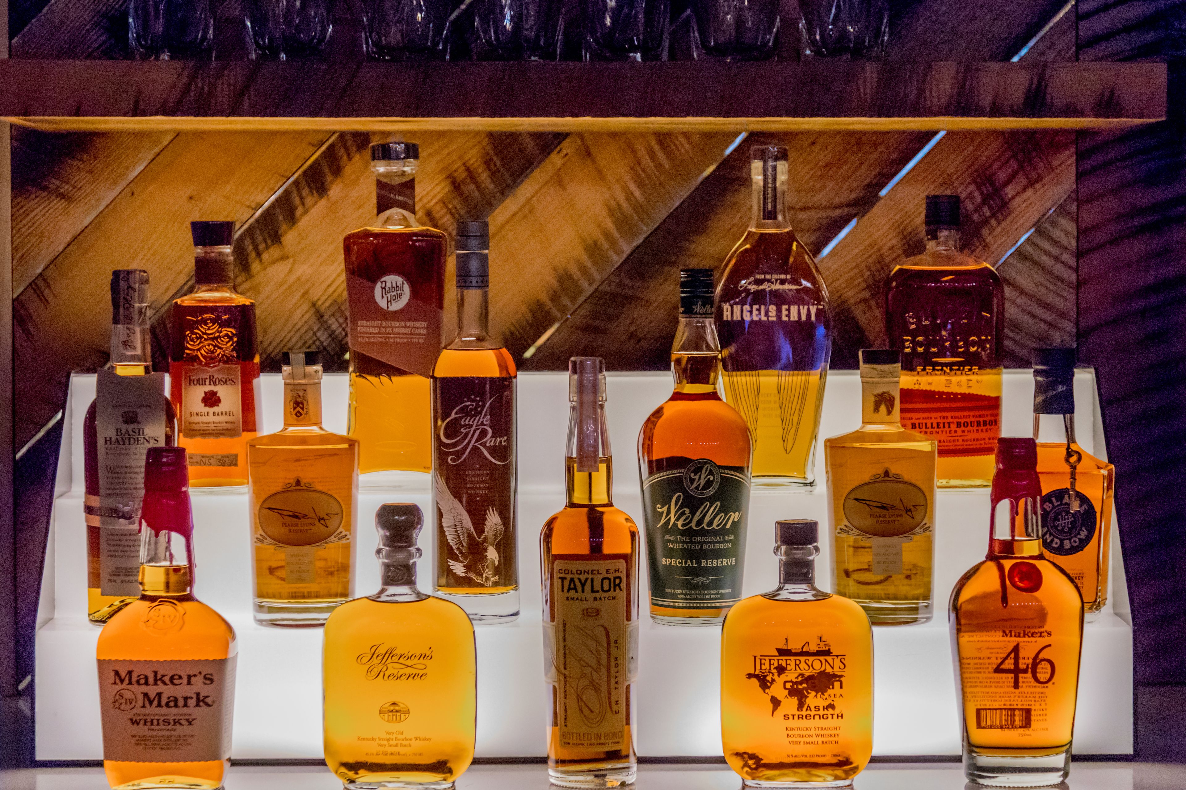 A display of various whiskey bottles arranged on a wooden shelf.