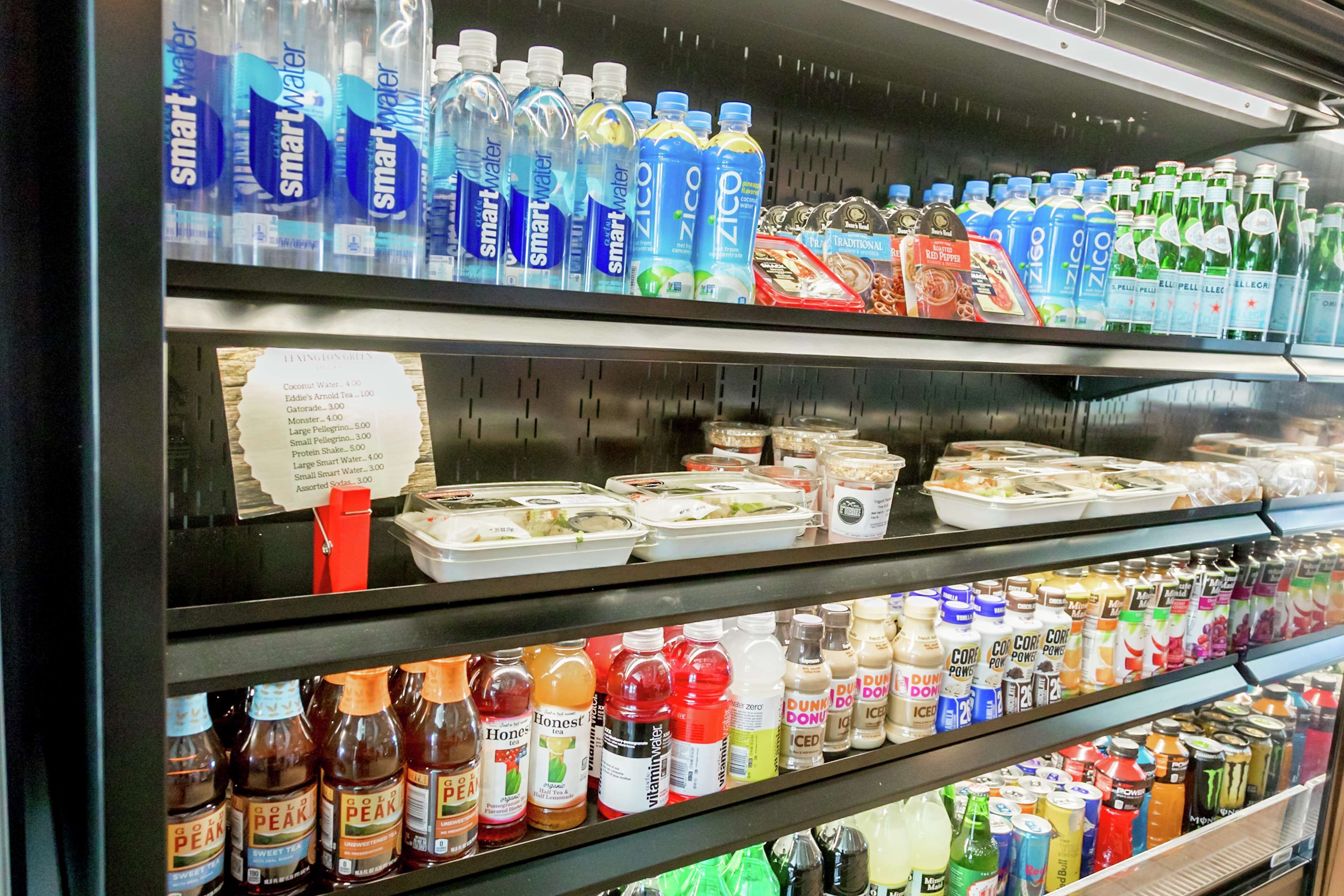 A refrigerated display case in a store with various bottled beverages and food items.