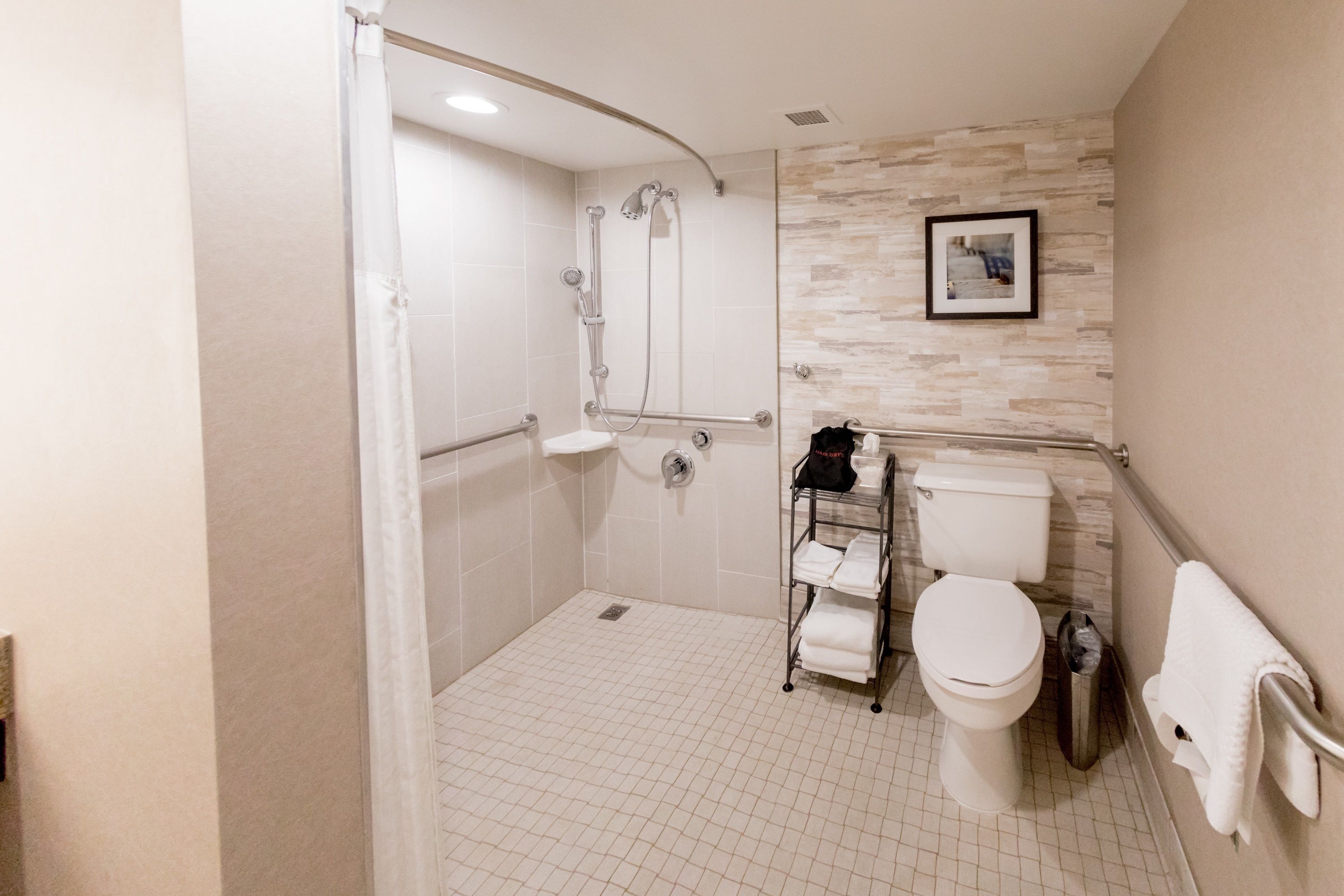 A modern bathroom with a shower, toilet, and a towel rack.