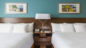 A hotel room with two beds, a nightstand with a lamp, and two framed pictures on the wall. - Fairfield Inn & Suites Cheyenne (Cheyenne)