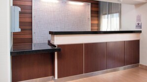A reception area with a wooden panel wall, a whiteboard, a reception desk, and a window with curtains. - Fairfield Inn & Suites Cheyenne (Cheyenne)