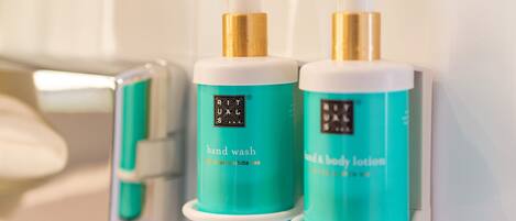 Two teal bottles of hand wash and body lotion with gold pumps, labeled 'RITUALS OF KARMA', placed on a white surface.