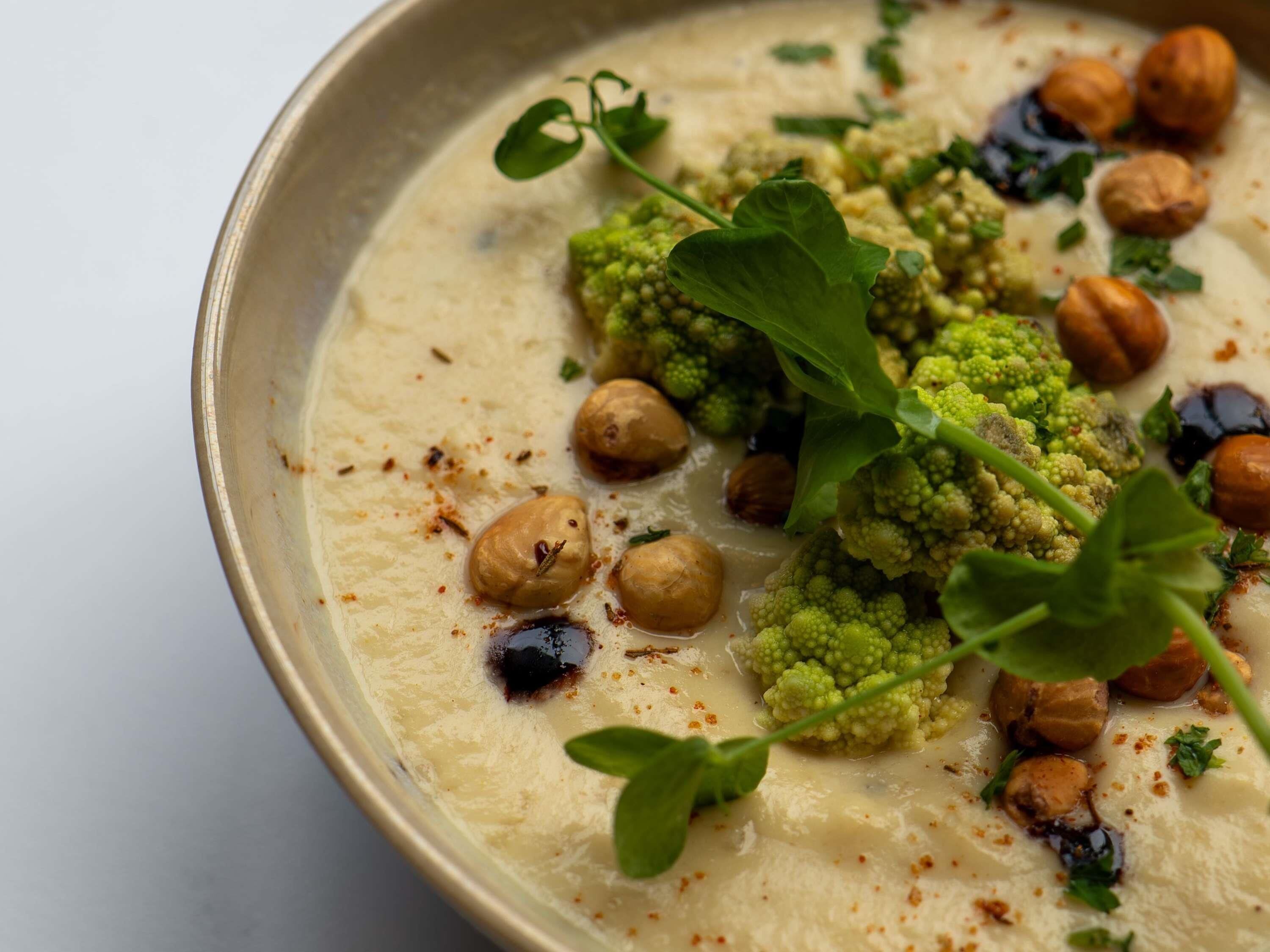 A bowl of food with chickpeas, green sauce, and herbs.