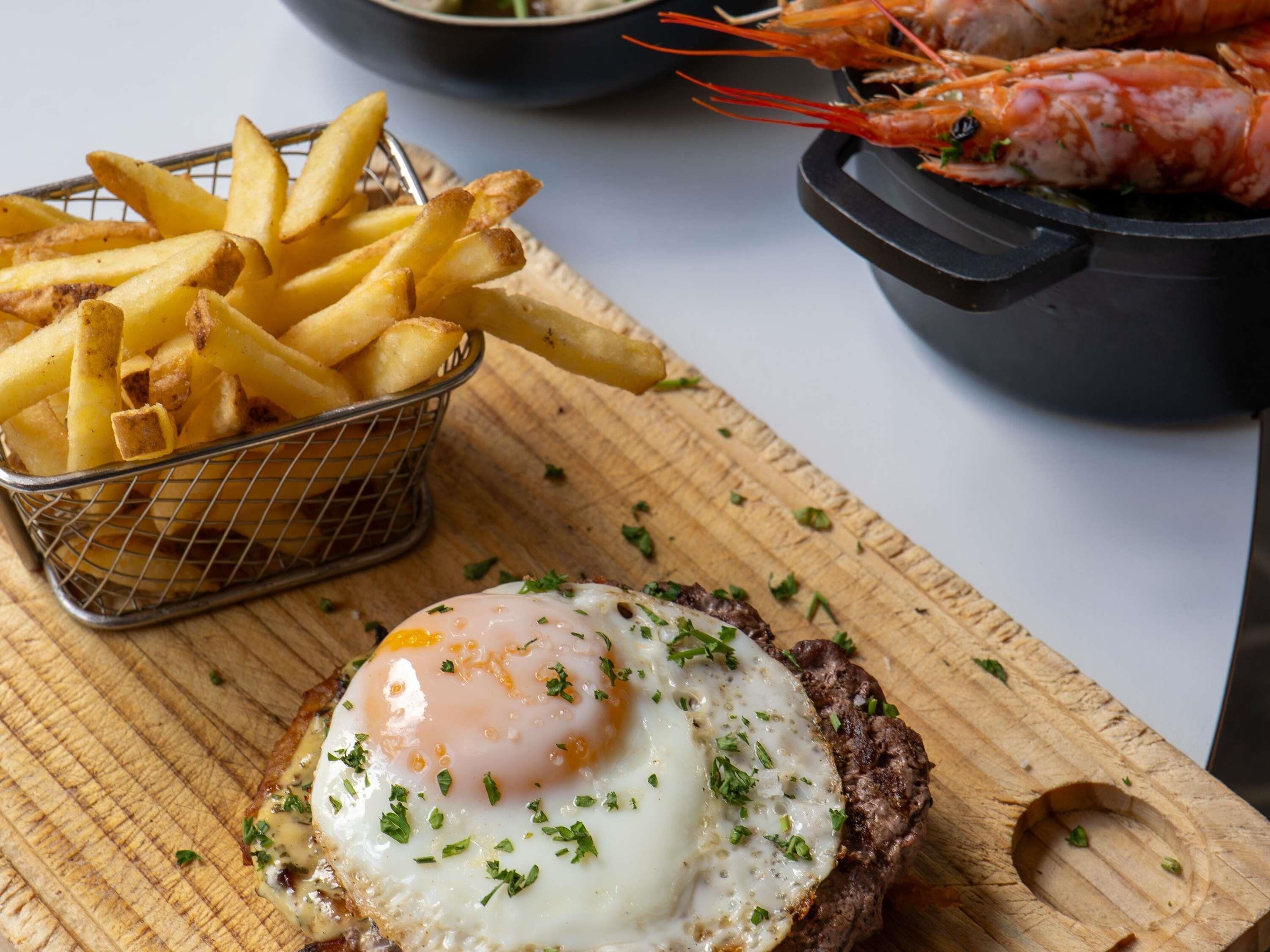 A meal with fries, shrimp, and a poached egg on toast.